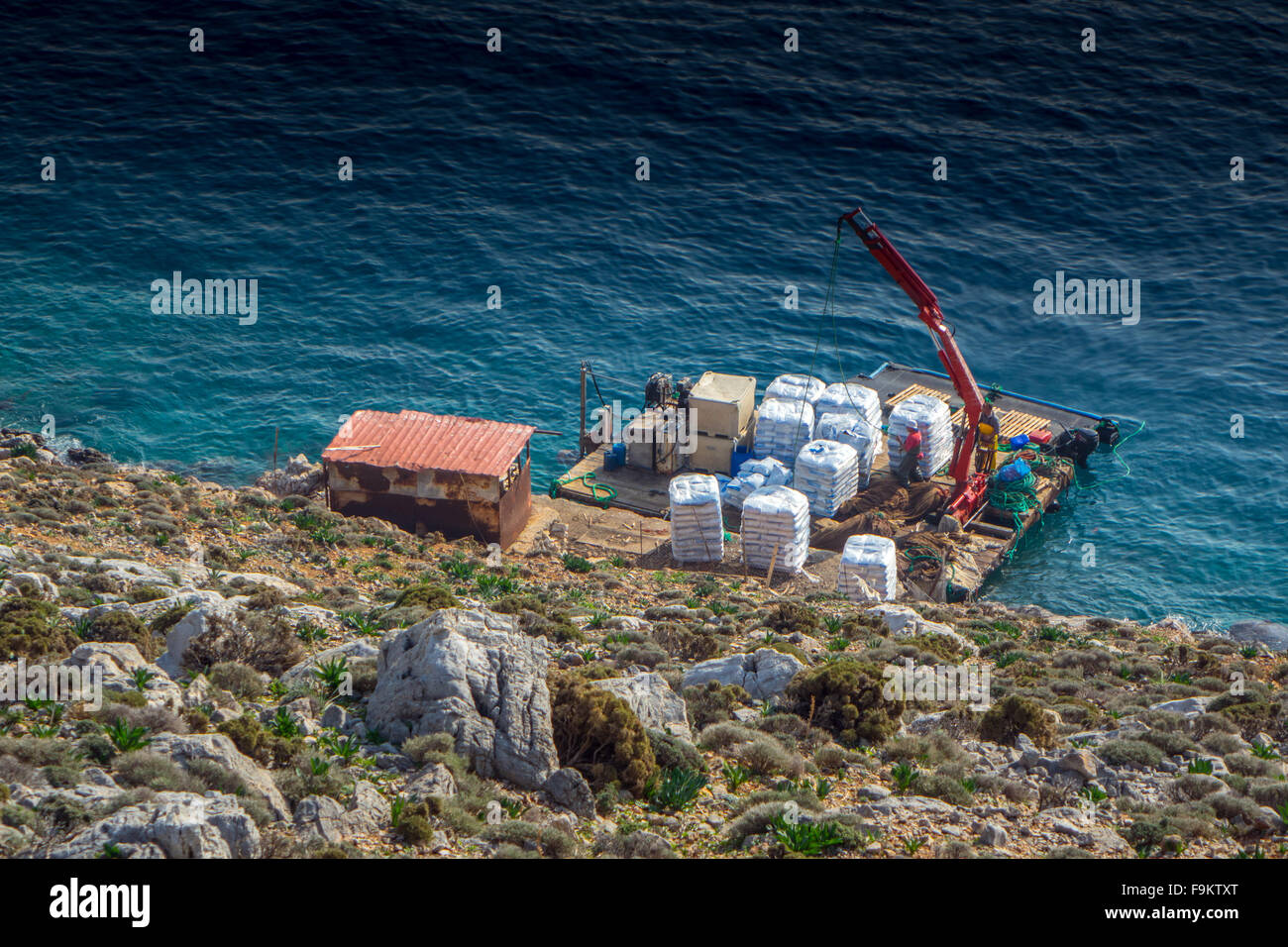 Radeau avec grue d'alimentation fournissant à l'élevage de poissons au large de Kalymnos, Grèce Banque D'Images
