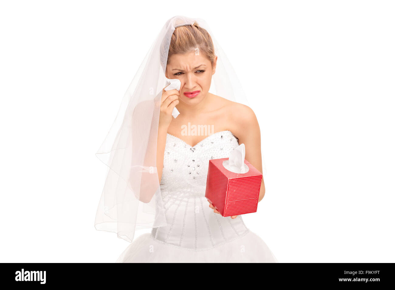 Jeune mariée dans une robe de mariage de pleurer et d'essuyer ses larmes isolé sur fond blanc Banque D'Images