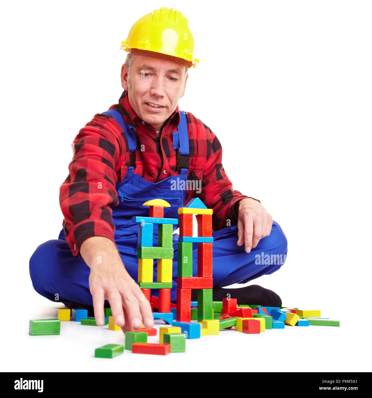 Travailleur de la construction principale à jouer avec de nombreuses briques colorées Banque D'Images