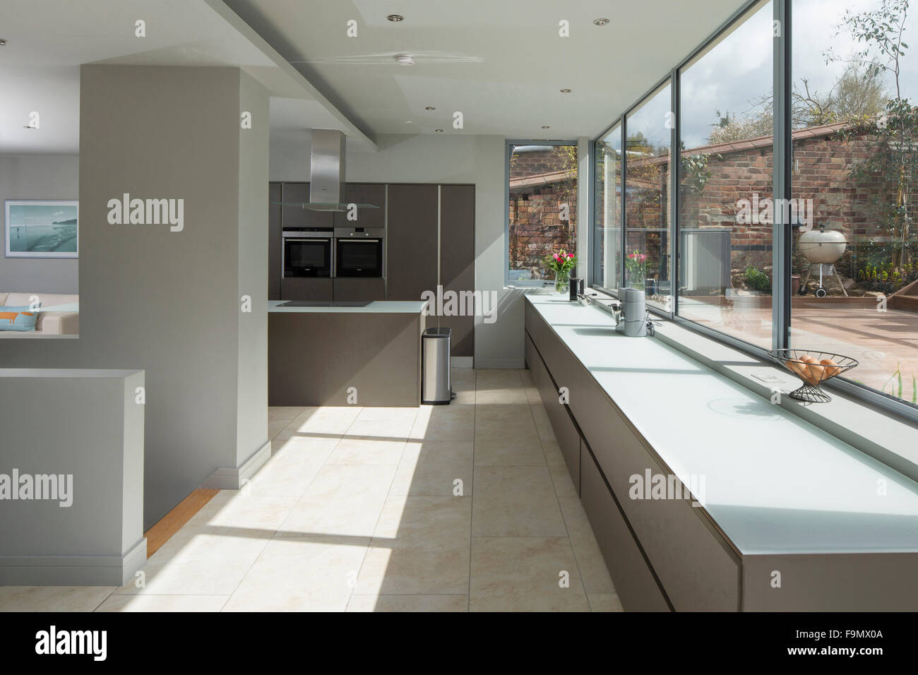 Un grand salon, une cuisine et salle à manger, avec vue sur le grand mur de verre pleine taille collés sur un patio. Les lignes pures et minimalistes murs unis. Banque D'Images