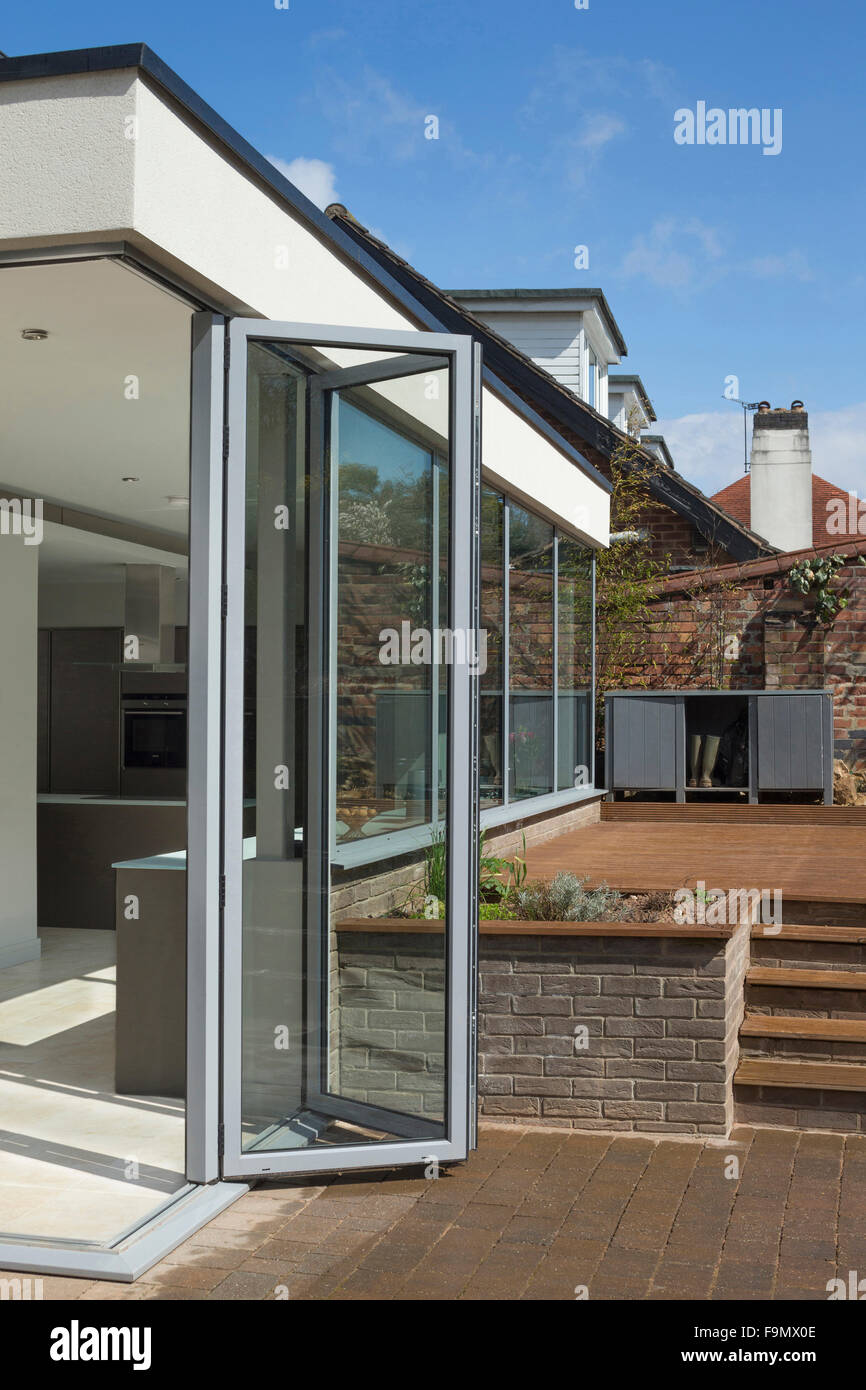 Arrière de la maison, et bi-fold de l'ouverture des portes de la Cuisine sur terrasse. Des murs de verre. Une maison familiale moderne. Banque D'Images