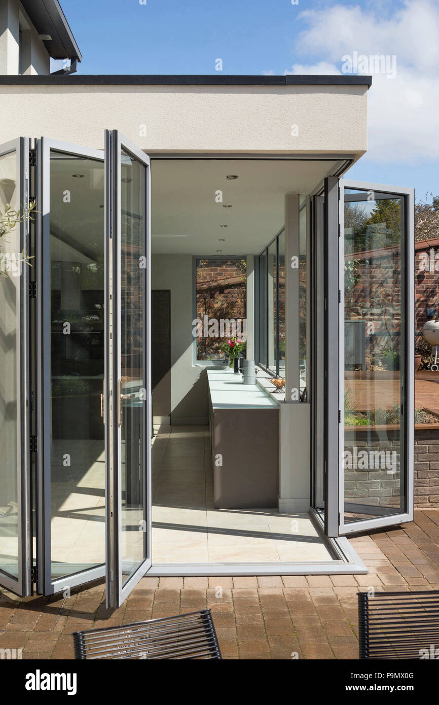 Arrière de la maison, et bi-fold de l'ouverture des portes de la Cuisine sur terrasse. Des murs de verre. Une maison familiale moderne. Banque D'Images