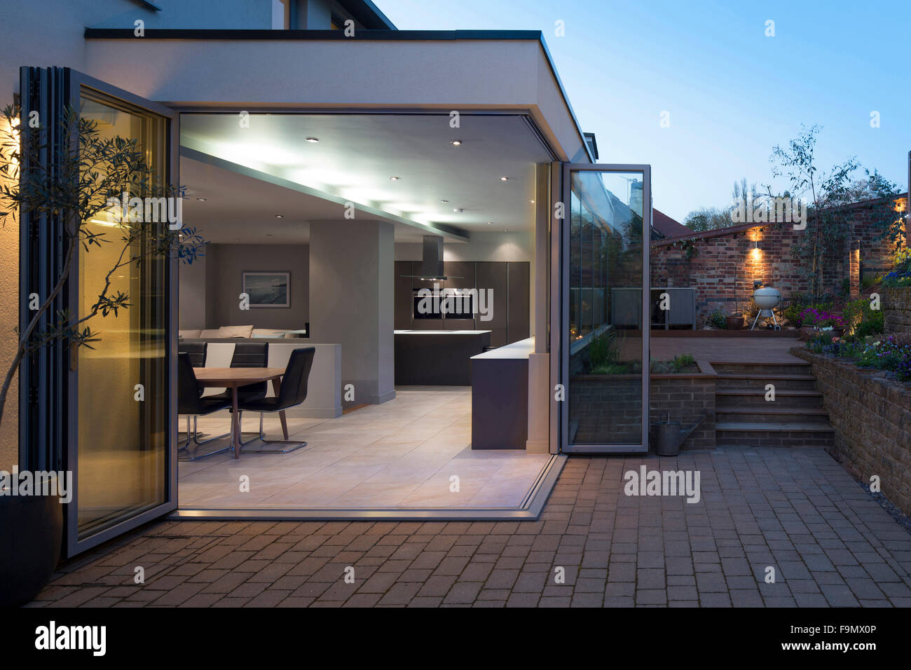 Cuisine et salle à manger vue par ouvrir les portes bi-fold depuis le patio et jardin au crépuscule. Une maison familiale moderne. Banque D'Images