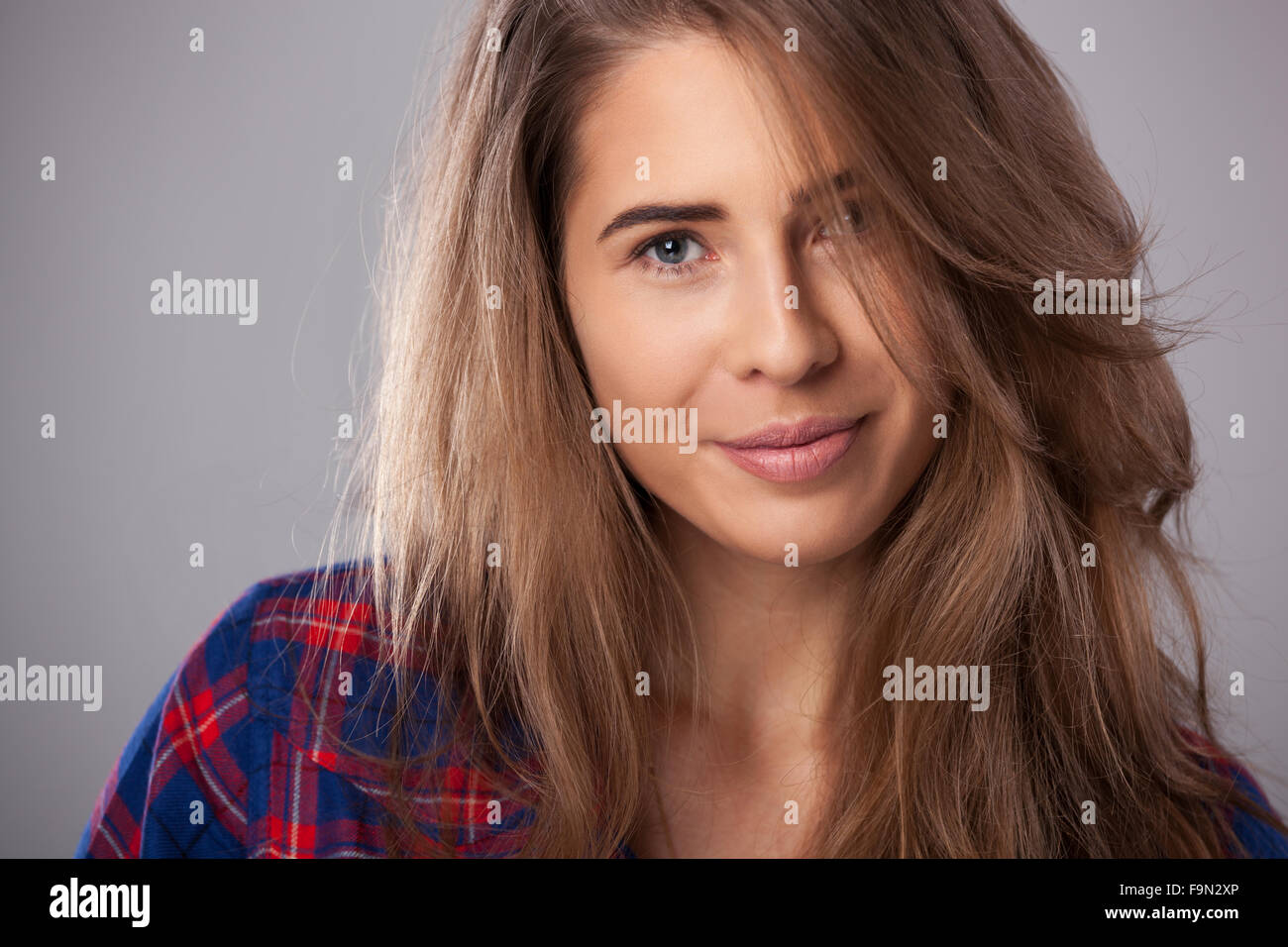 Studio portrait of happy young woman sur fond gris. Banque D'Images