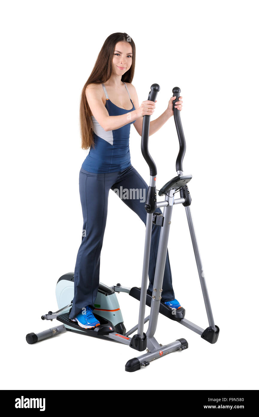 Jeune femme faisant des exercices sur l'entraîneur elliptique Banque D'Images