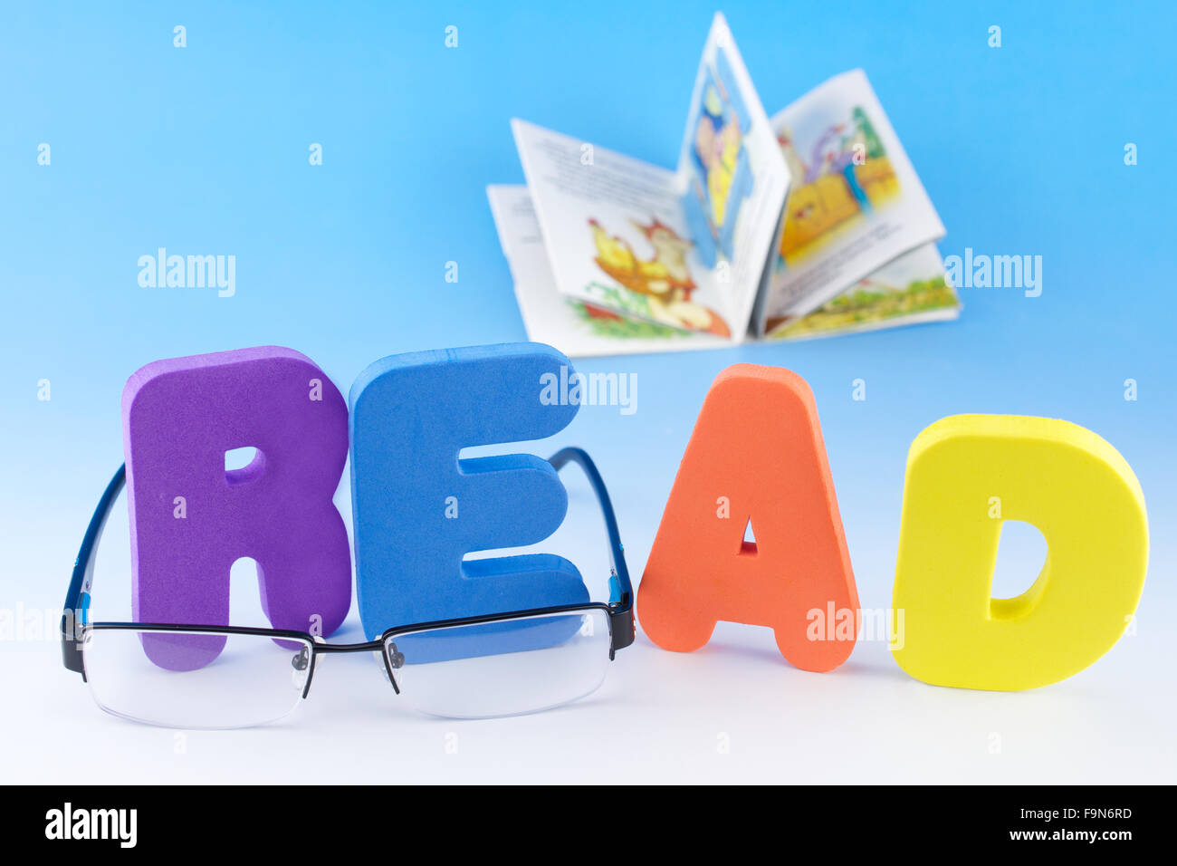 Lettres ABC Spell Read, lunettes et ouvert les enfants livre sur fond bleu Banque D'Images