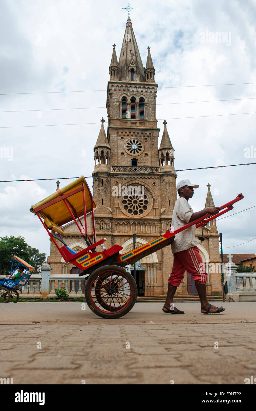 Un Pous Pous conducteur par la cathédrale dans le centre d'Antsirabe à Madagascar. Banque D'Images