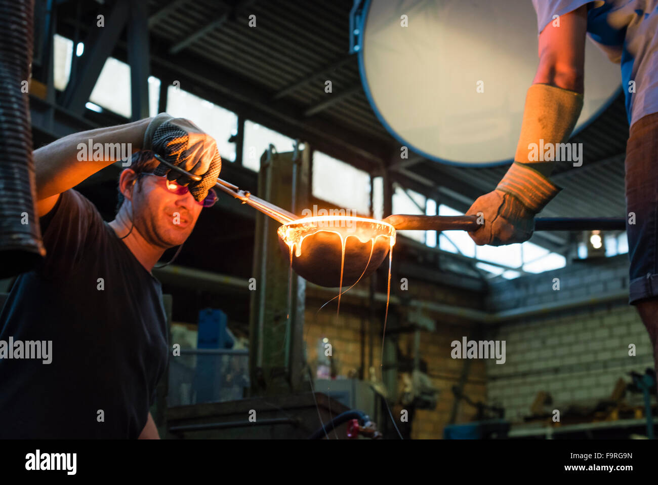 Souffleurs travailler devant du four à l'usine de verre de Hergiswil, Suisse, sont la manipulation de verre fondu dans une boule. Banque D'Images