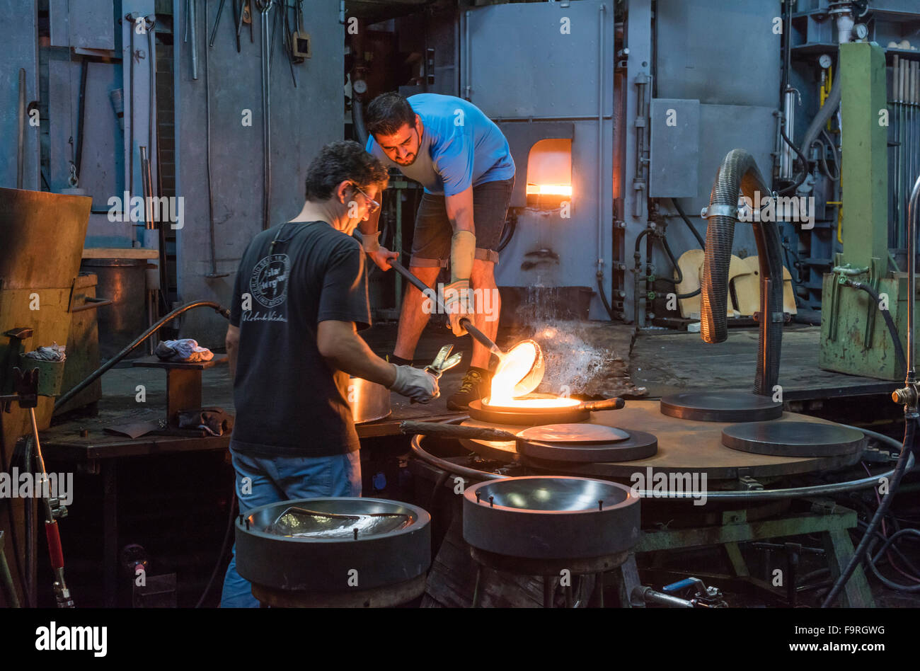 Souffleurs travailler devant du four à l'usine de verre de Hergiswil, Suisse, affluent de verre fondu dans un moule. Banque D'Images