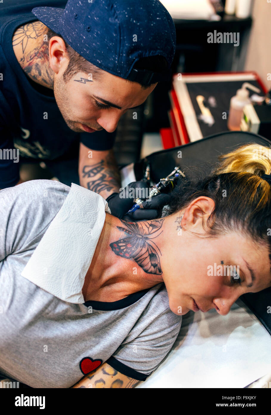 Femme qui reçoit à son cou tatouage papillon Banque D'Images