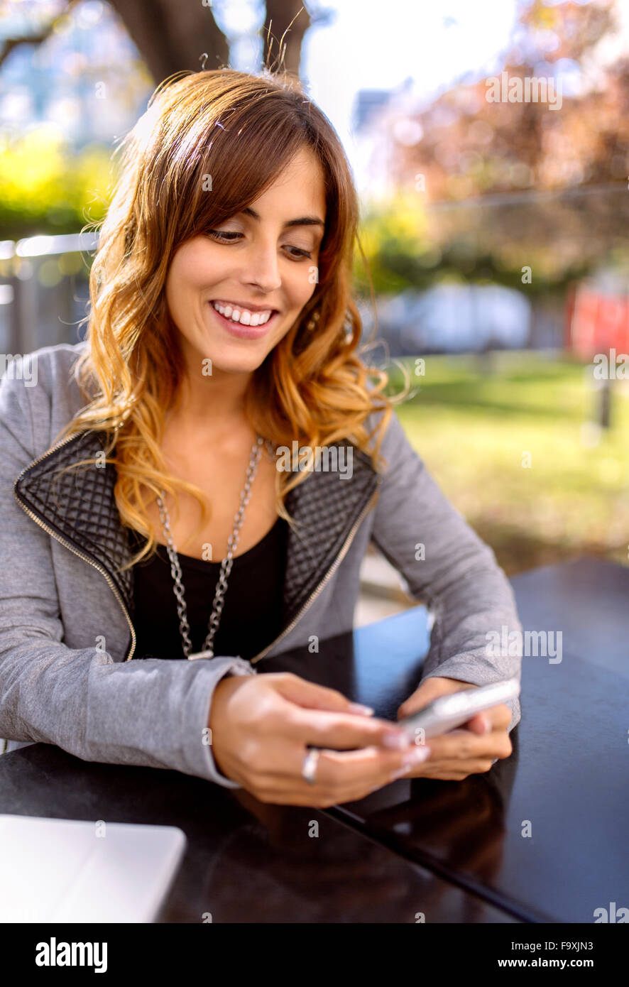Portrait of happy young woman looking at her smartphone Banque D'Images