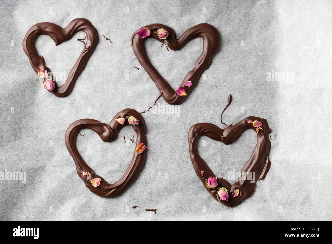 Quatre coeurs au chocolat avec des fleurs rose Banque D'Images