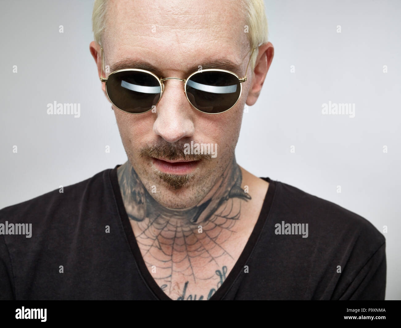 Portrait of man with tattoo et cheveux teints blonde wearing sunglasses Banque D'Images