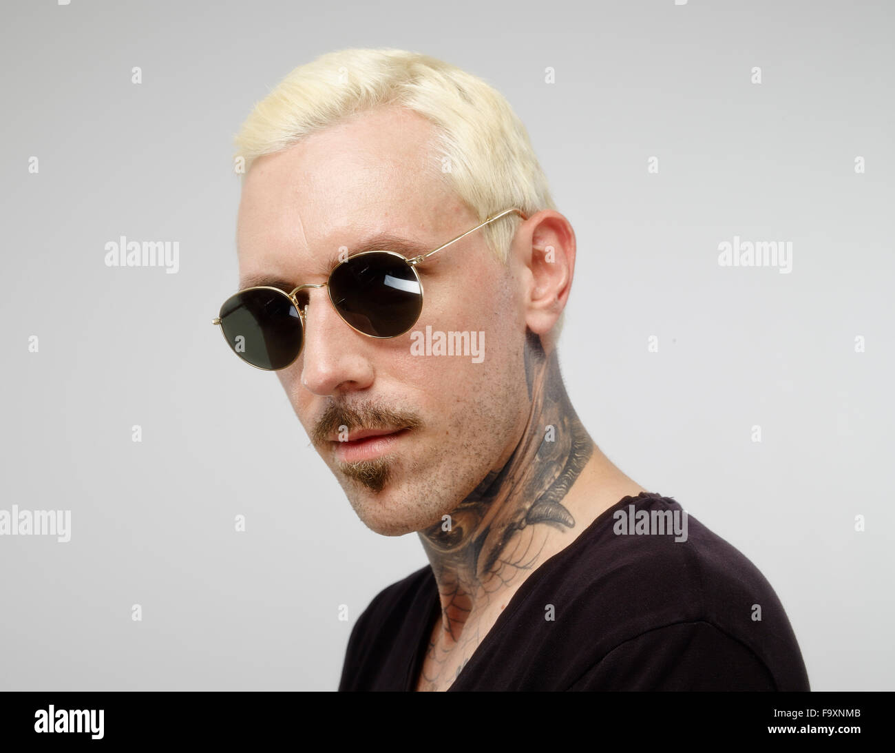 Portrait of man with tattoo et cheveux teints blonde wearing sunglasses Banque D'Images