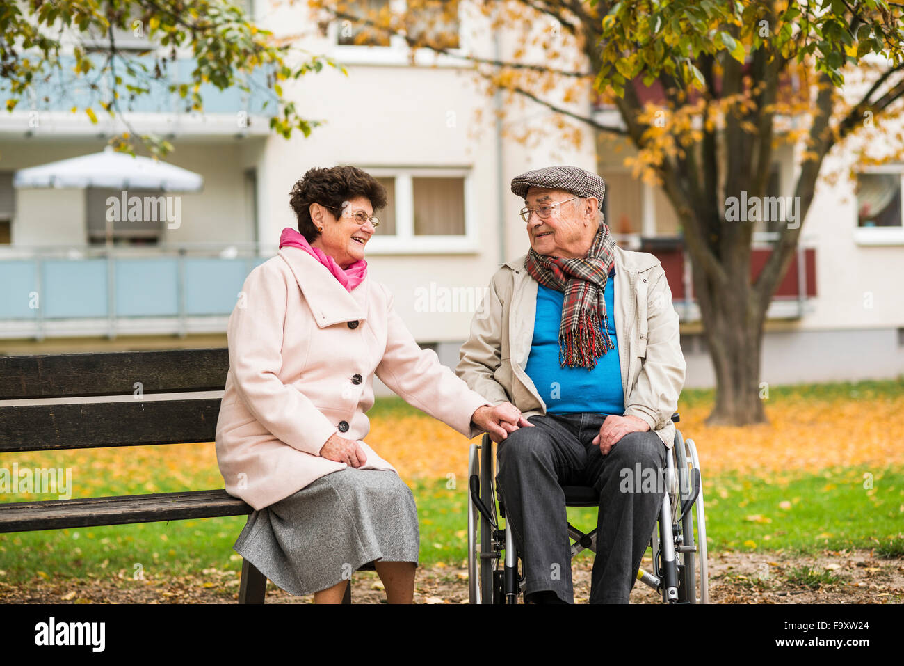 Hauts femme assis sur un banc à côté de mari en fauteuil roulant Banque D'Images