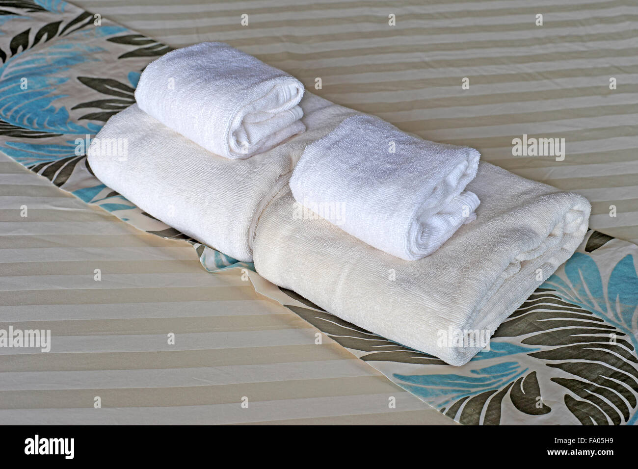 Serviettes de bain blanc roula et empilés sur le lit Banque D'Images