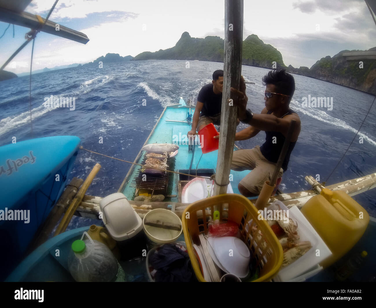 Les hommes à l'arrière d'un bateau en bois faire un barbecue Banque D'Images