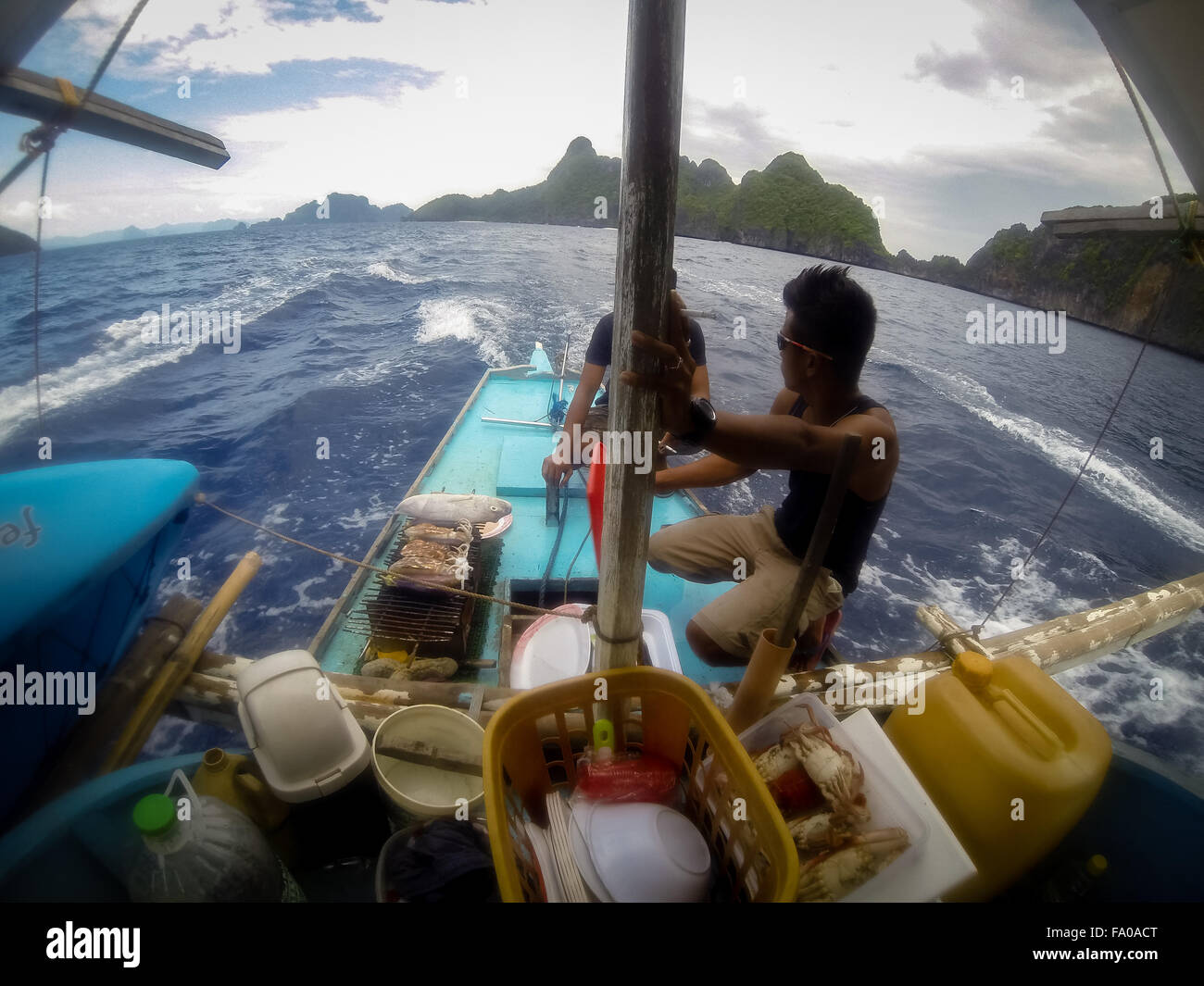 Les hommes à l'arrière d'un bateau en bois faire un barbecue Banque D'Images