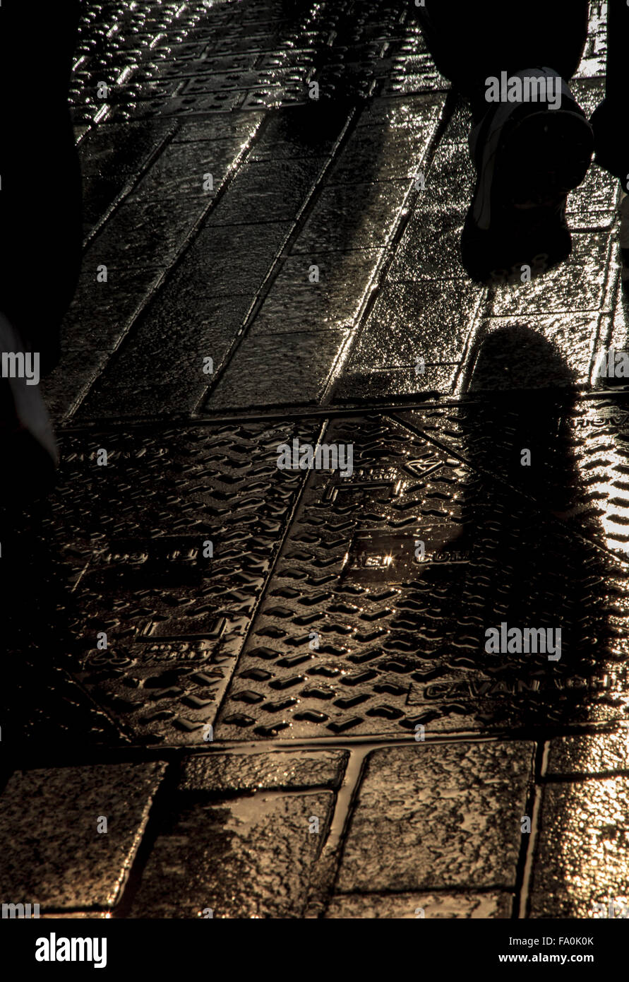 Réflexions sur un pied la chaussée mouillée à Cork en Irlande. Banque D'Images