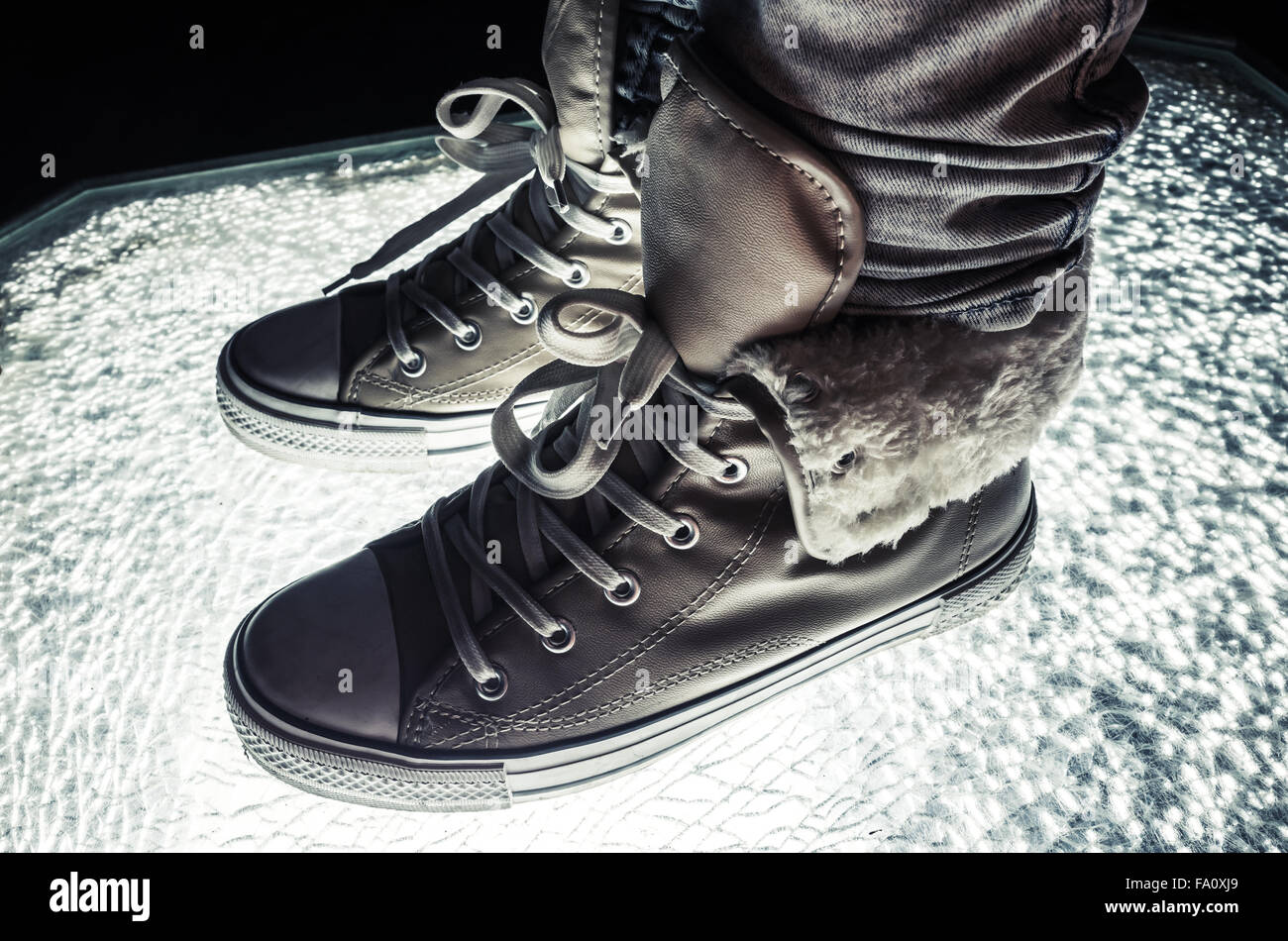 Chaussures de sport, chaussures chaudes debout sur verre fissuré, correction tonale froid, retro style contraste filtre photo Banque D'Images