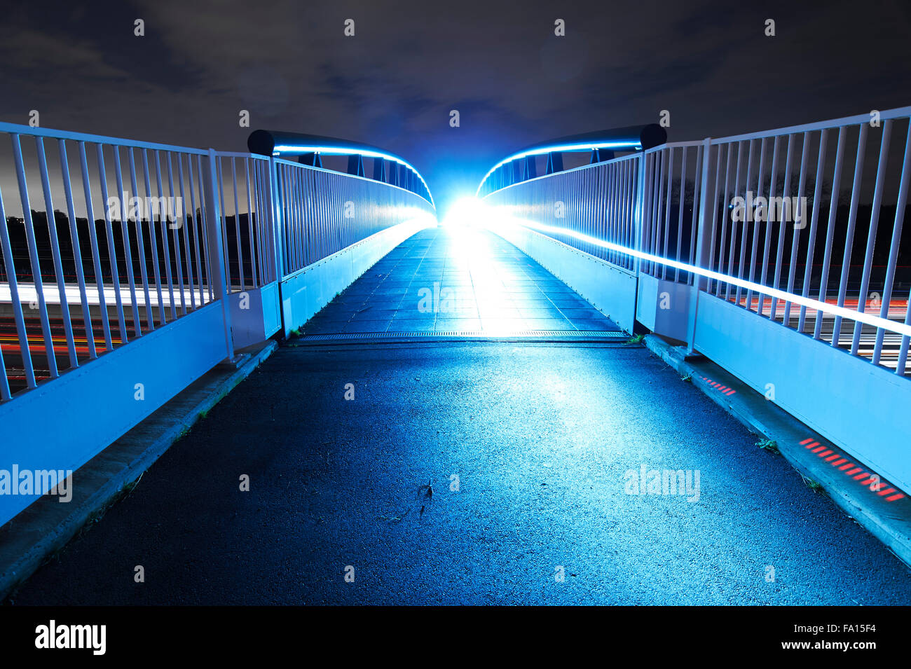 Cycliste franchissant la passerelle au-dessus de l'A46 avec des feux de vélo éclairant la passerelle, Bingham, dans le Nottinghamshire, Royaume-Uni Banque D'Images