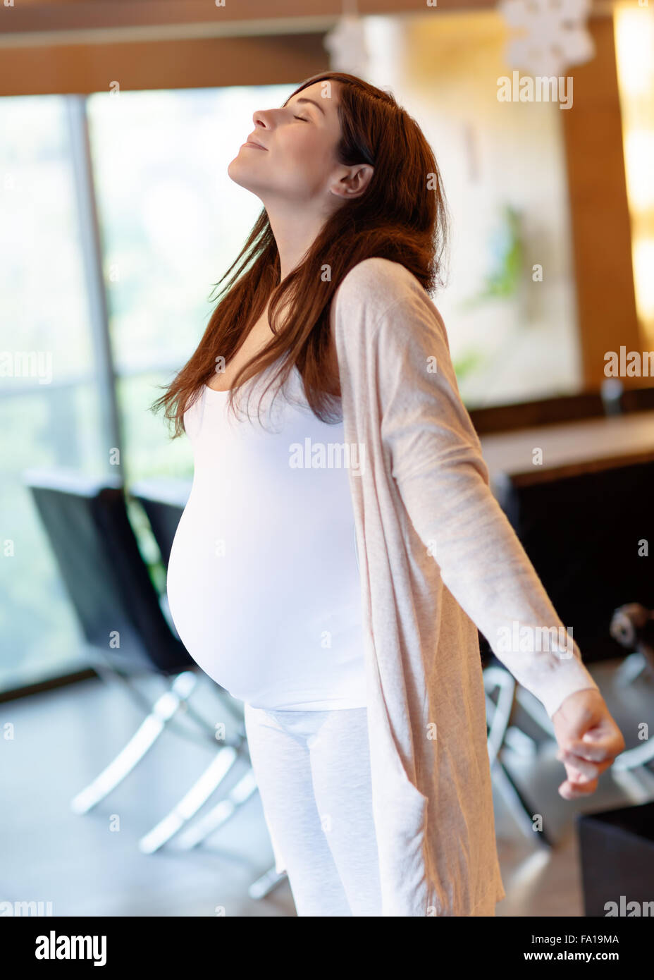 Calme belle femme enceinte aux yeux clos l'article à la maison le matin et en méditant, en faisant de l'exercice de yoga Banque D'Images