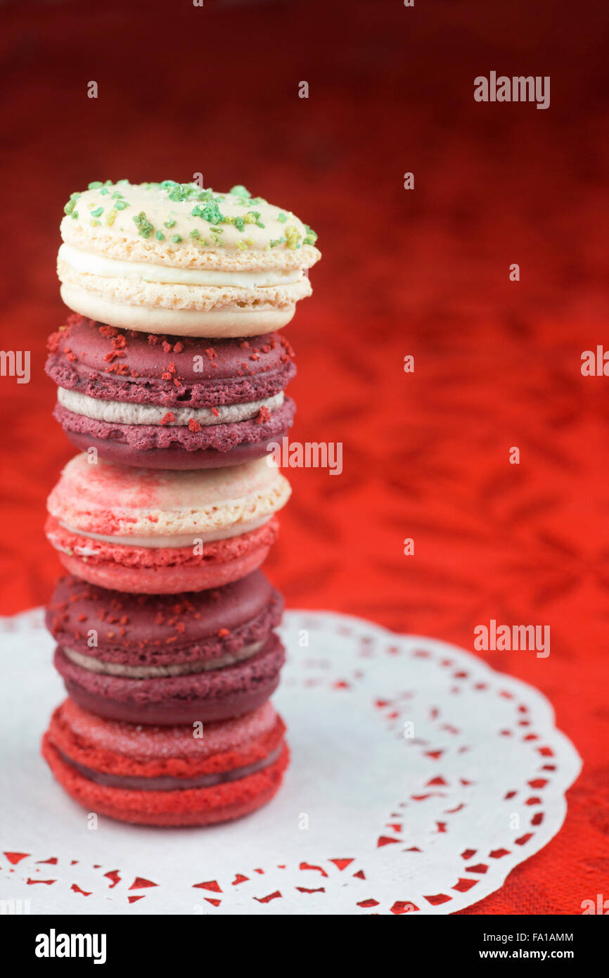 Pile de macarons Noël, vanille et basilic, canneberge givrée, canne de Noël et vin chaud saveurs sur nappe rouge Banque D'Images