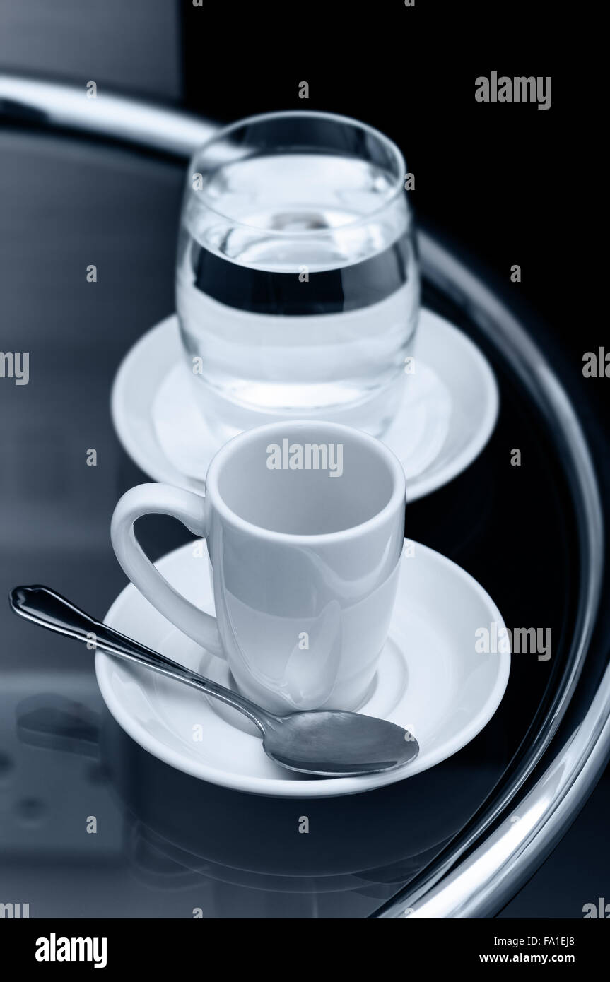 Café Espresso tasse vide et verre d'eau sur la table de chevet closeup Banque D'Images