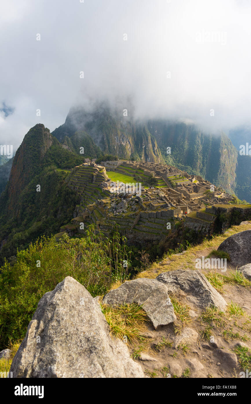 Machu Picchu illuminée par les premiers rayons du soleil qui sort de l'ouverture des nuages. La ville de l'Inca est le plus visité de voyage Banque D'Images