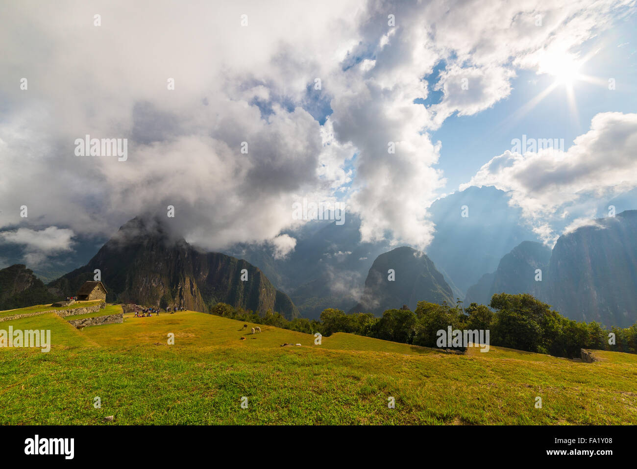 Machu Picchu illuminée par la lumière du soleil du matin. Vue grand angle depuis les terrasses panoramiques avec rétroéclairage ci-dessus dans le ciel. Banque D'Images