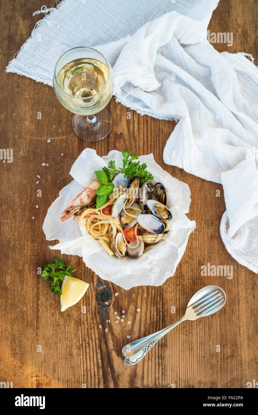 Pâtes aux fruits de mer. Linguine aux palourdes et crevettes au bol, verre de vin blanc sur fond de bois rustique, vue du dessus Banque D'Images