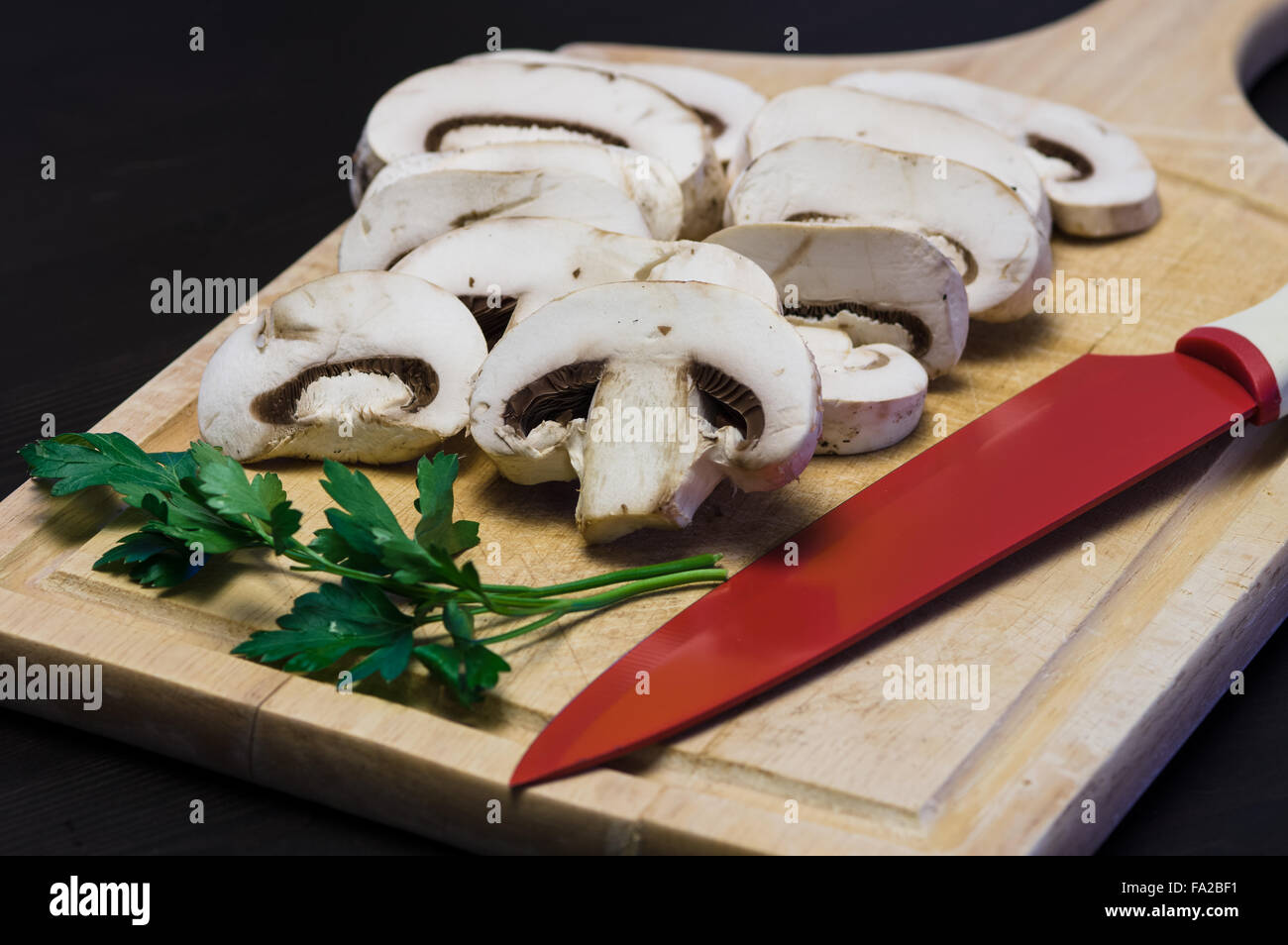 Champignons crus sur la planche à découper sur fond noir Banque D'Images