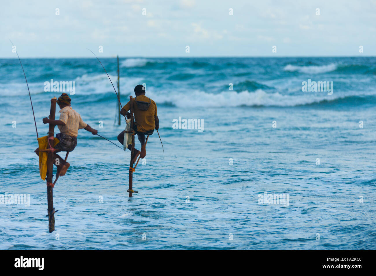 Pêcheurs sur pilotis du Sri Lanka haut élevée au-dessus de l'eau séance de pêche de capture de petits d'une manière traditionnelle entourée d'un grand o Banque D'Images