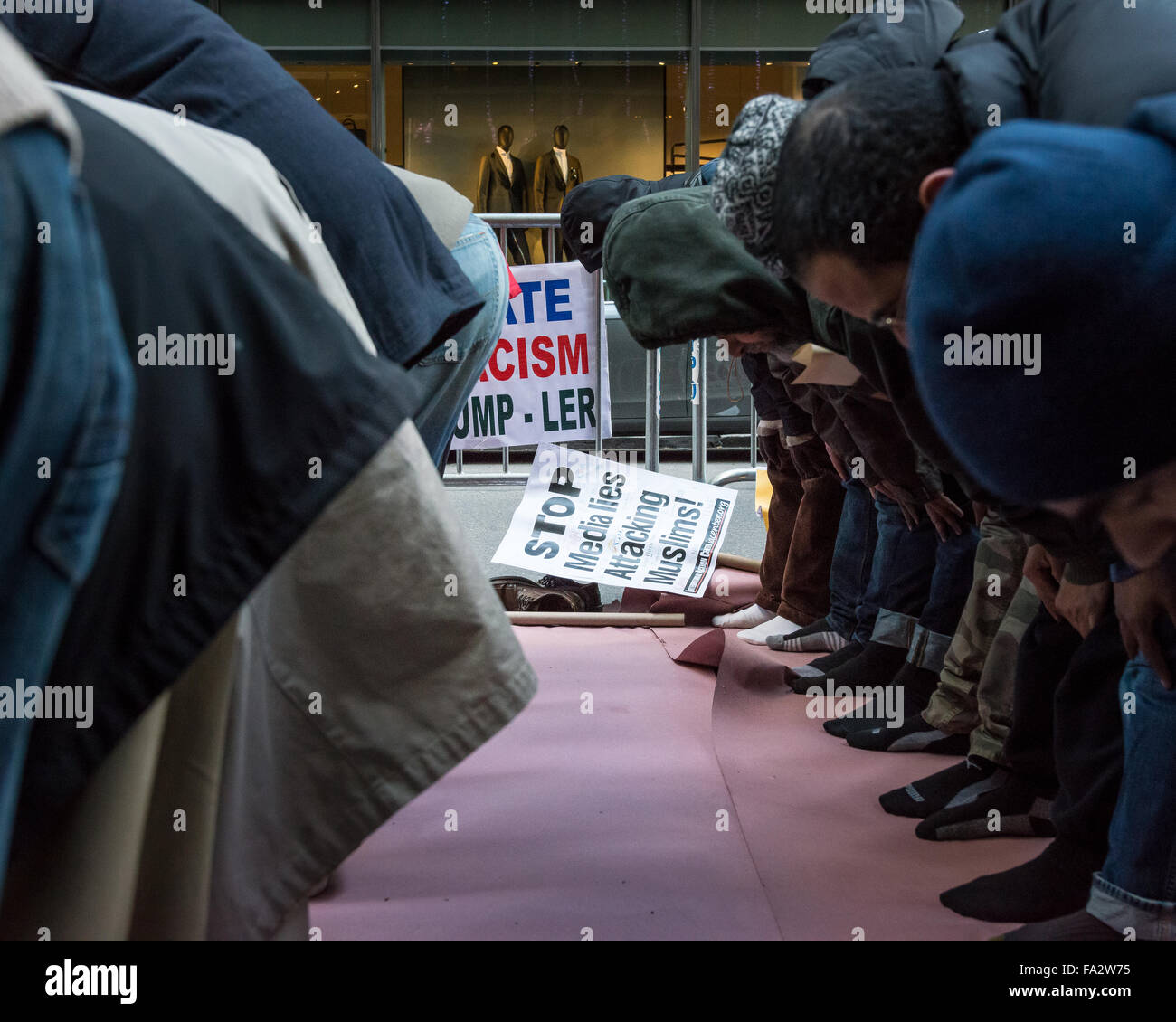 New York, États-Unis. 18Th Oct, 2015. Muslim-American les hommes à partir d'une mosquée locale prier en face de Trump Tower comme un signe utilisé dans la démonstration s'appuie contre une barricade de la police. Plusieurs centaines de manifestants se sont rassemblés à l'extérieur de la Trump Tower à l'East 56th Street et de la Cinquième Avenue à Manhattan pour condamner candidat présidentiel républicain Donald Trump's position sur l'immigration ; après le rallye pendant près de deux heures, les manifestants ont défilé à Herald Square. Credit : Albin Lohr-Jones/Pacific Press/Alamy Live News Banque D'Images