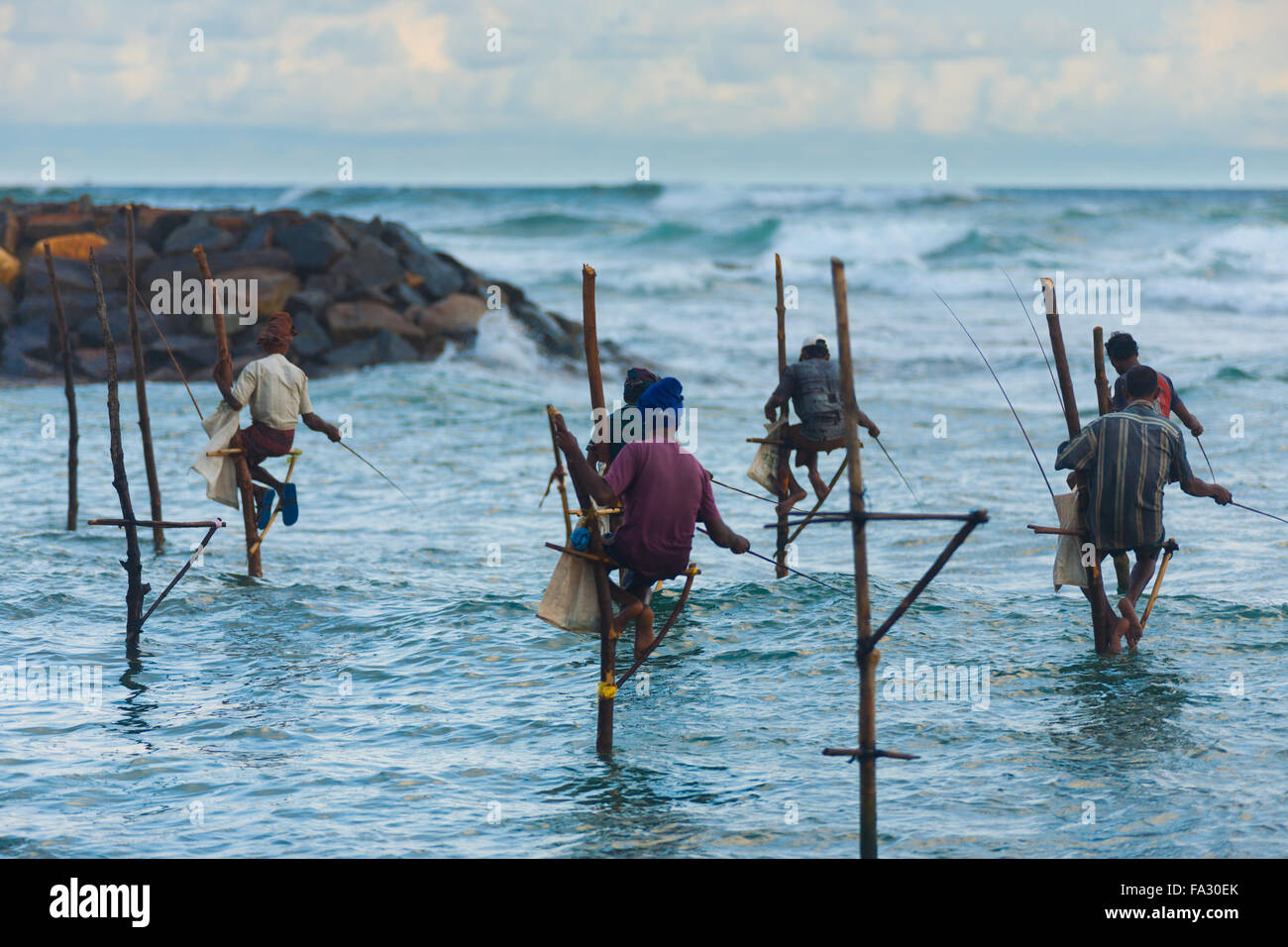 Pêcheurs sur pilotis Sri-Lankais assis sur pilotis au-dessus de l'eau La pêche de petits poissons de l'océan en méthode traditionnelle unique Banque D'Images