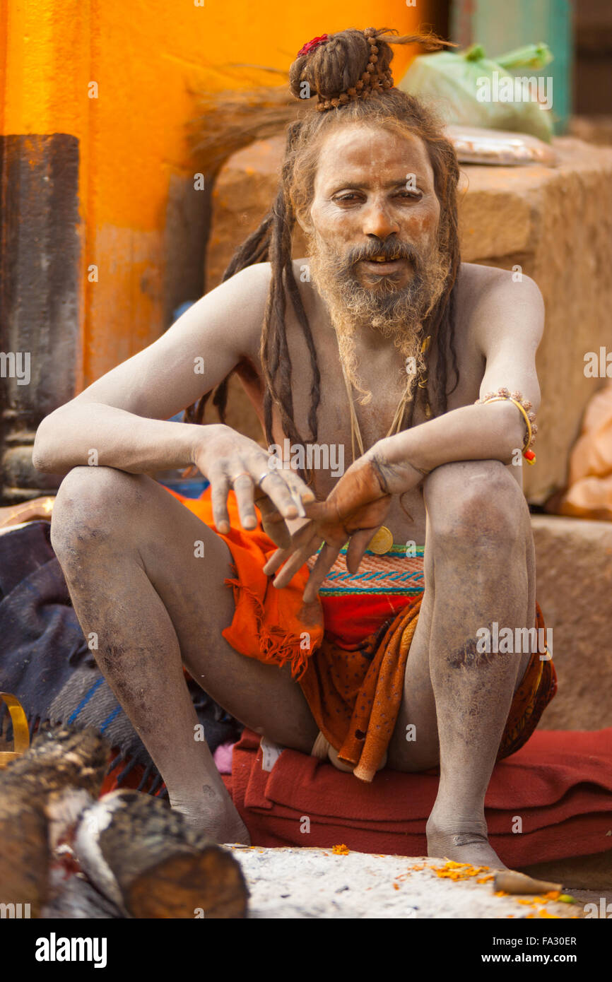 Un naga sadhu baba, la peau couverte de cendres, assis sur le ghat le long du Gange Banque D'Images