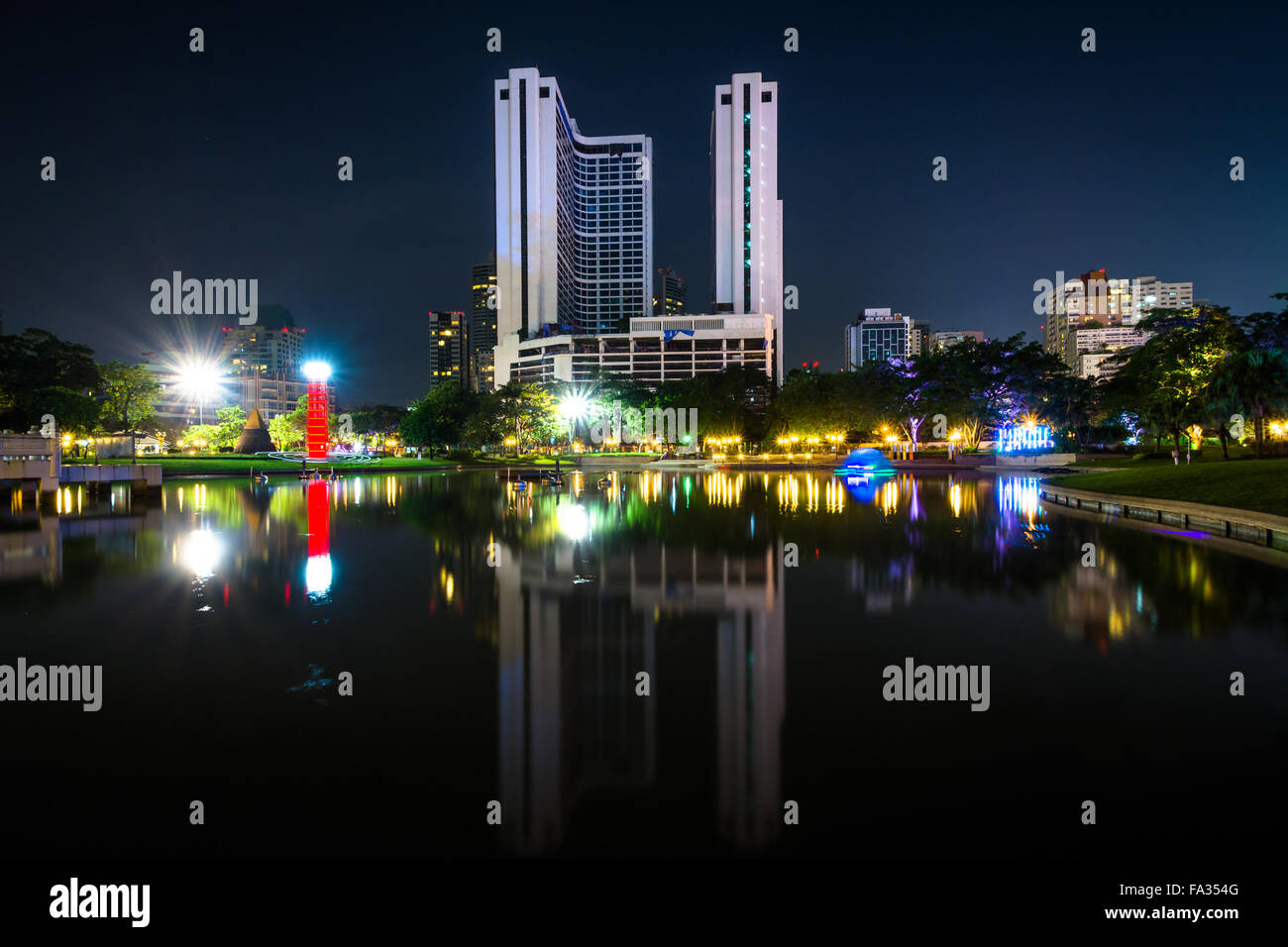 Les gratte-ciel modernes et du lac la nuit, vu au parc Benjasiri, à Bangkok, Thaïlande. Banque D'Images