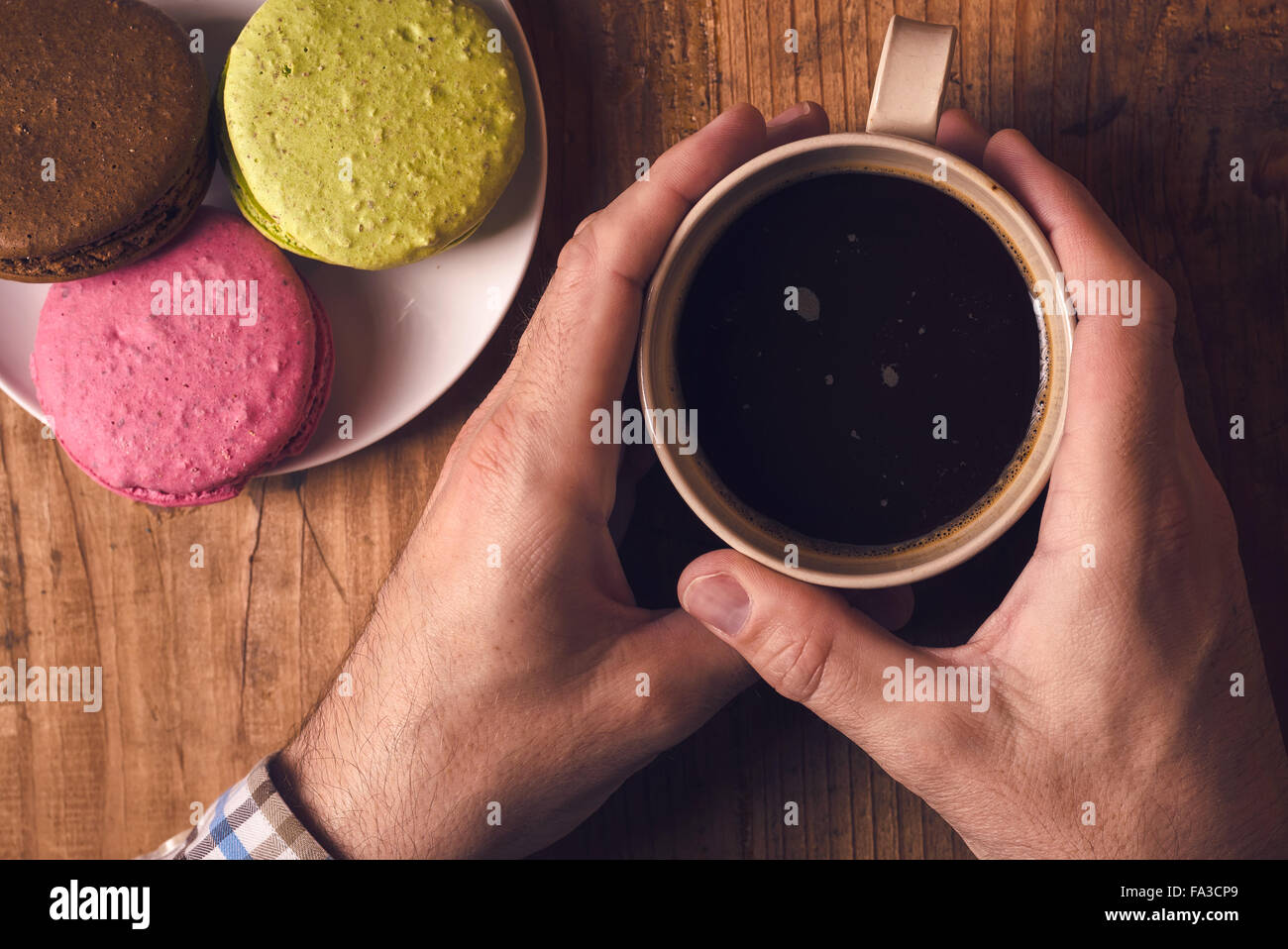 Tasse de café chaud et biscuits macaron sur la table le matin, male hands holding cup avec boisson chaude, vue d'en haut, aux couleurs rétro Banque D'Images