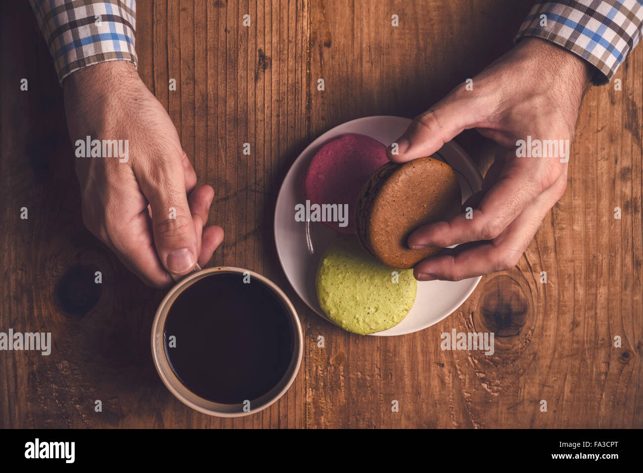 Du café et des Biscuits macaron sur la table le matin, male hands holding cup avec boisson chaude, vue d'en haut, aux couleurs rétro Banque D'Images