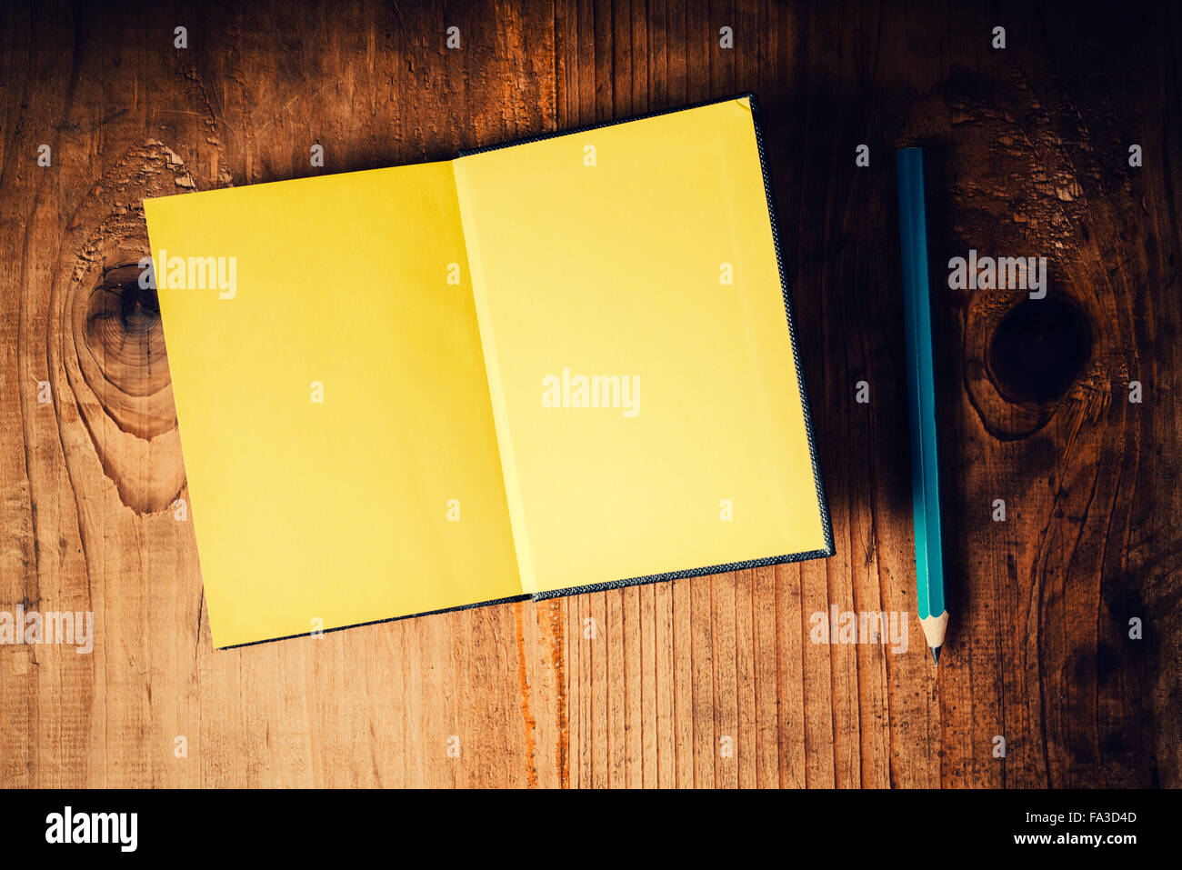 Vue de dessus de l'ordinateur portable ouvert avec des pages vierges et un crayon sur le vieux bureau en bois, tons rétro comme image copy space Banque D'Images