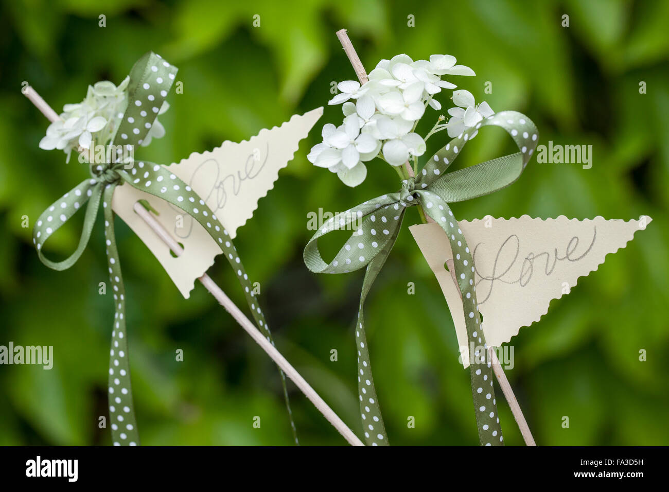 Matériel : papier, ciseaux en zigzag, perforatrice, ruban, crayons,  brochettes, hortensia à fleurs. Méthode : Trim triangle en utilisant des  ciseaux en zigzag. Faire deux trous avec le poinçon d'un côté plaque.