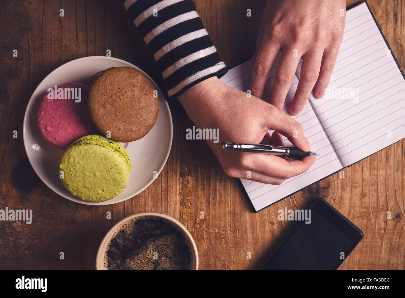Businessman au petit-déjeuner, vue du dessus de la main avec un crayon, tasse de café, un téléphone mobile et macaron cookie Banque D'Images