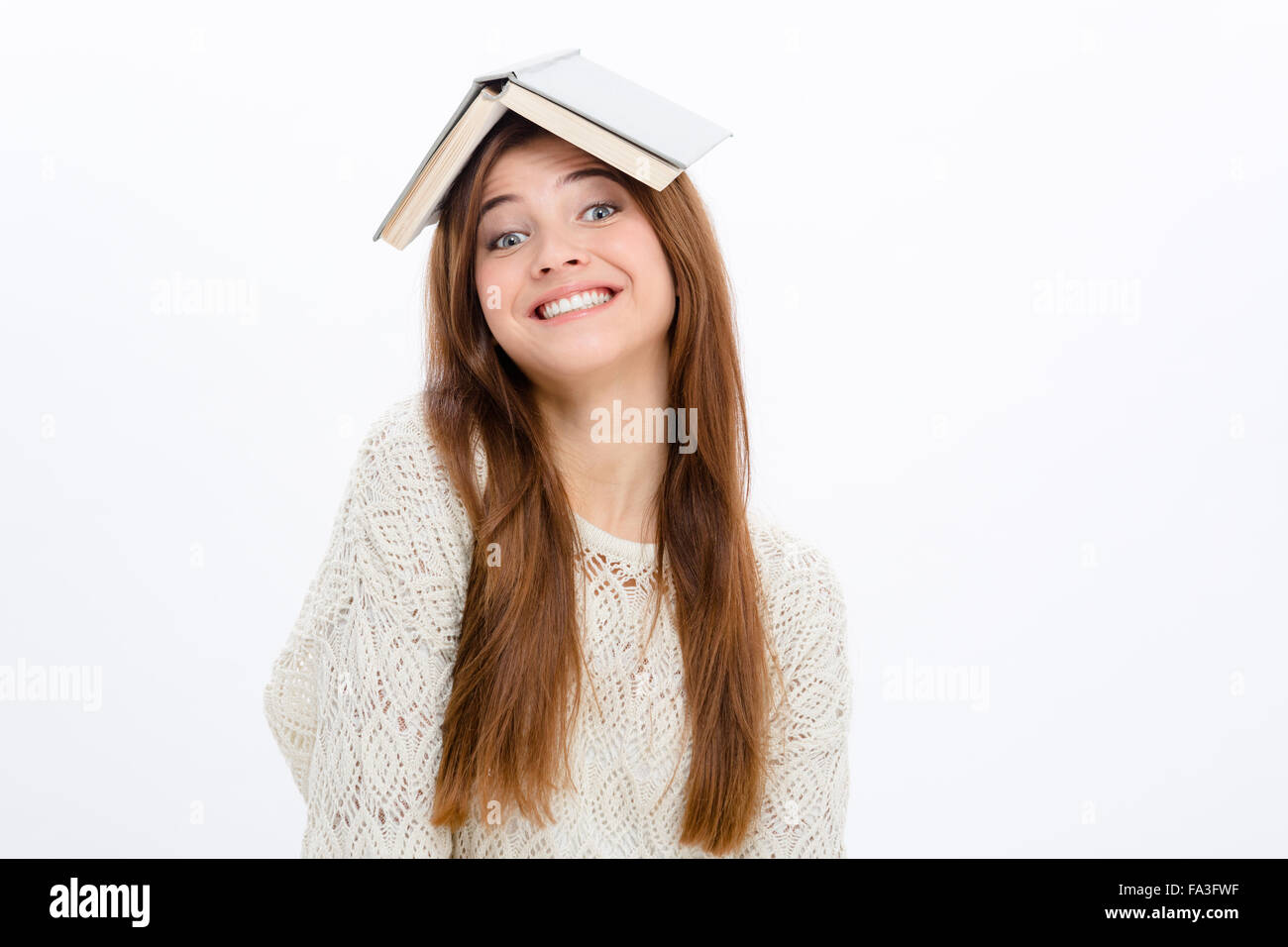 Jeune femme gaie comique ludique avec livre ouvert sur sa tête sur fond blanc Banque D'Images