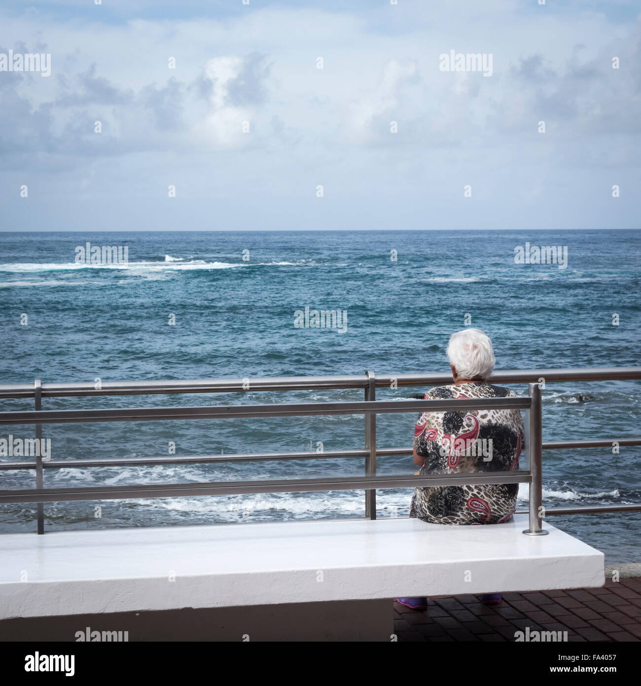 Femme âgée assise sur banc avec vue sur la mer en Espagne. Banque D'Images