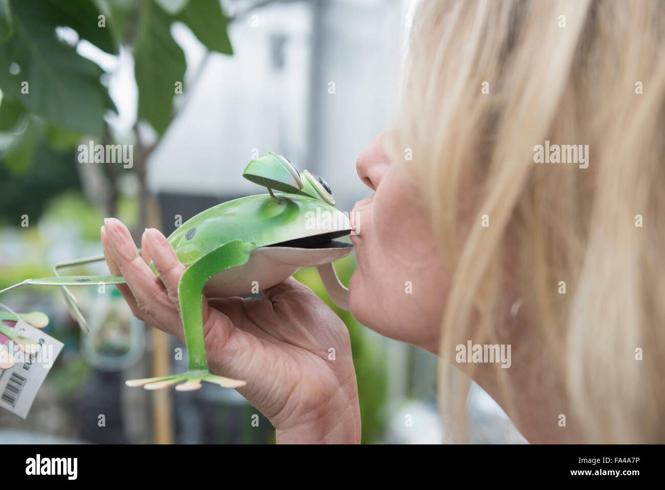 Woman kissing une grenouille en métal garden centre, Augsbourg, Bavière, Allemagne Banque D'Images