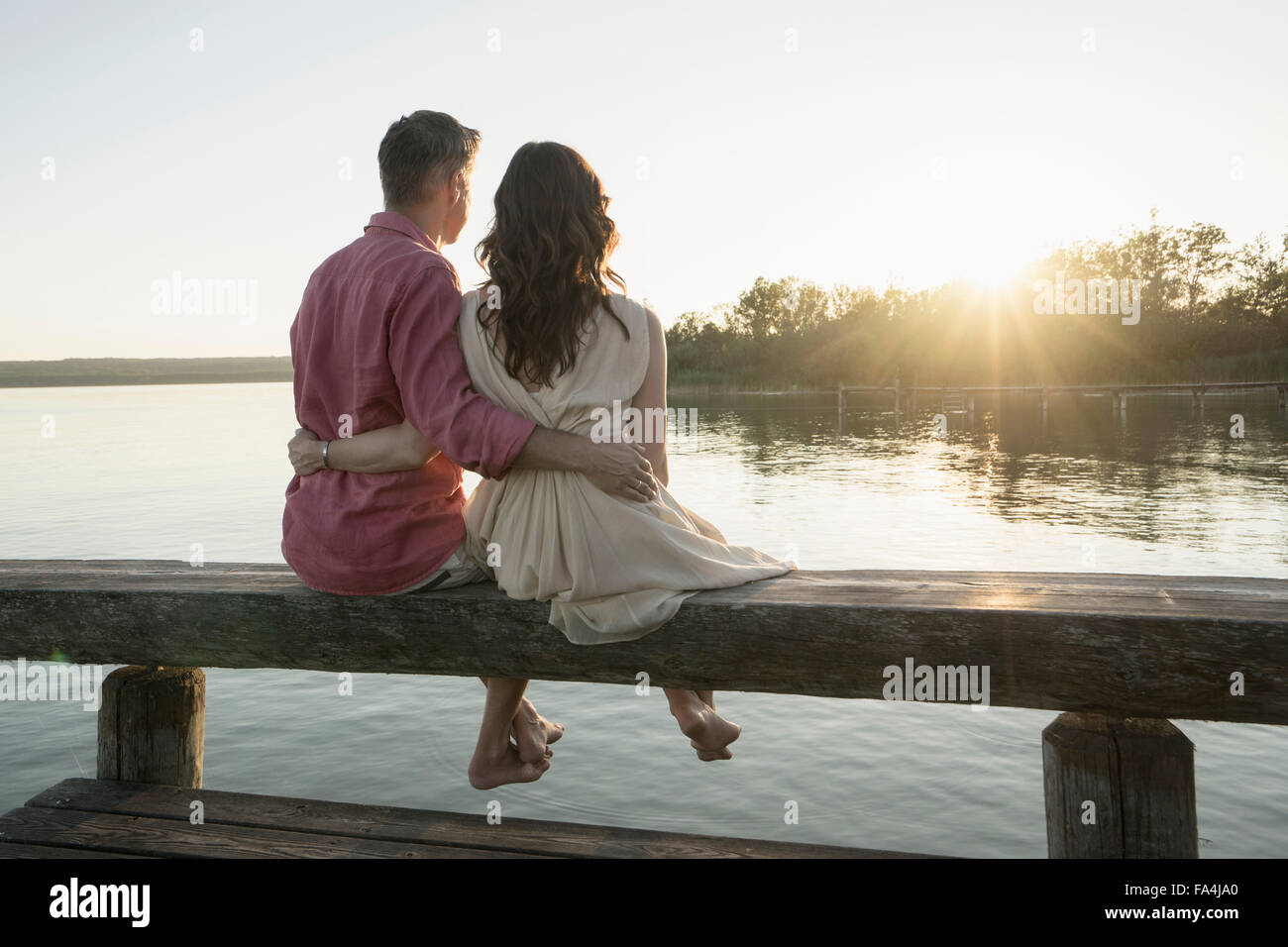 Young couple sitting on pier à au coucher du soleil, Bavière, Allemagne Banque D'Images