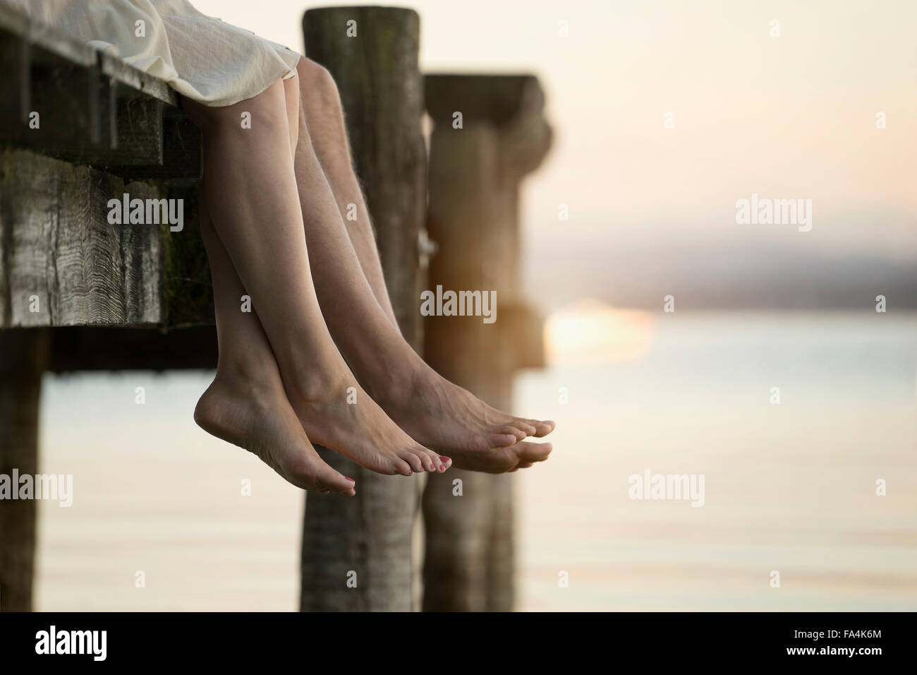 Couple les jambes pendantes sur la jetée, Bavière, Allemagne Banque D'Images