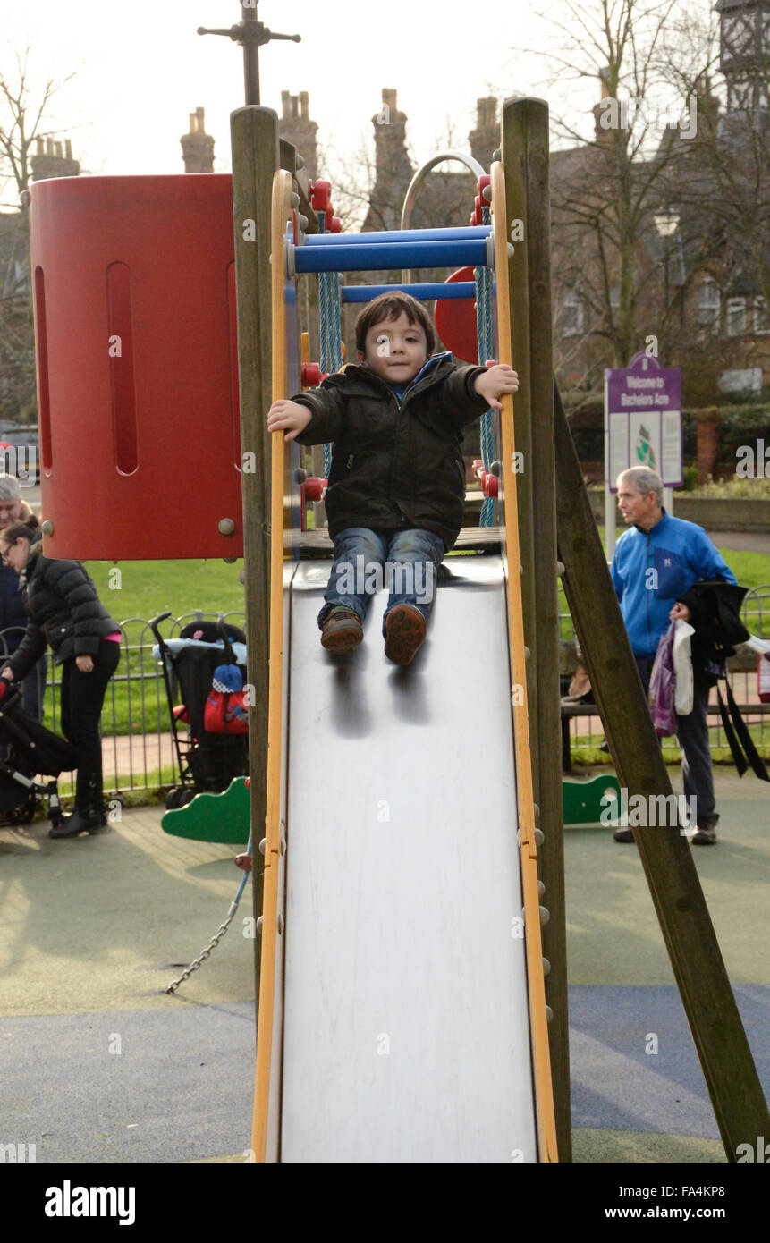 Un jeune garçon joue sur une diapositive dans une aire de jeux. Banque D'Images