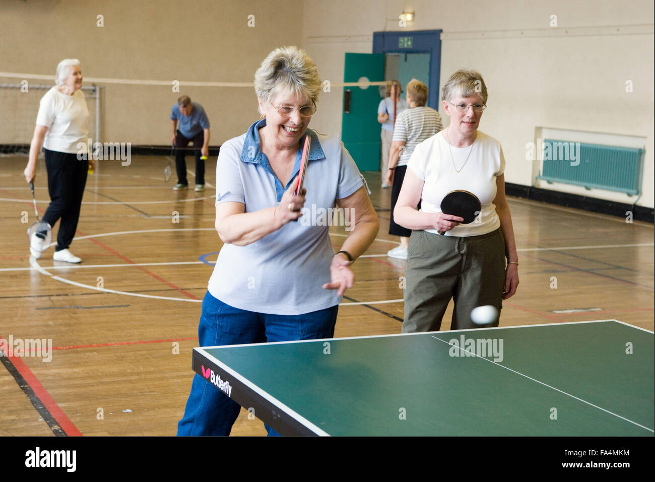 Groupe de femmes âgées à jouer au tennis de table et de badminton en salle de sport, Banque D'Images