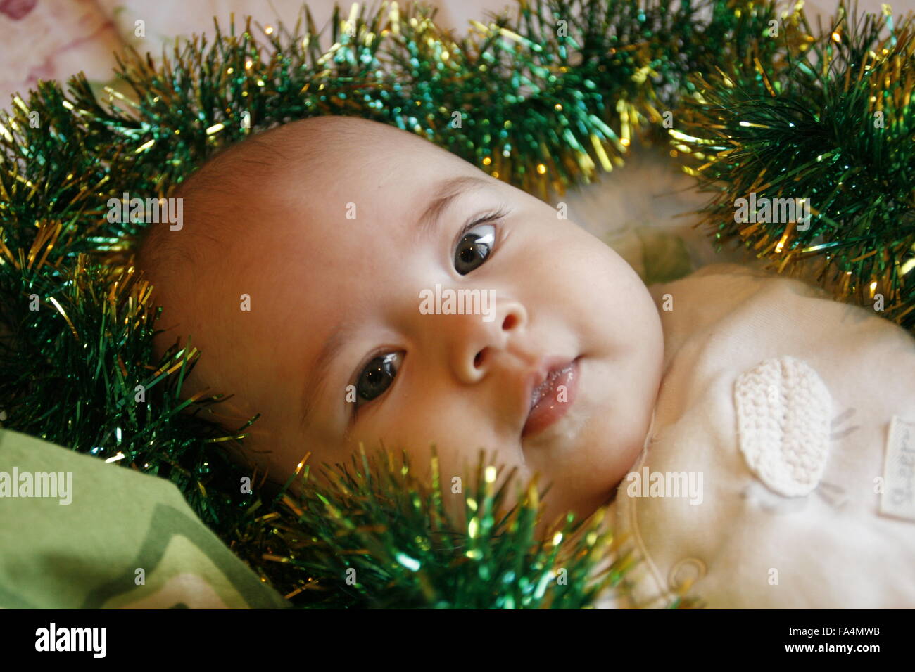 Un petit bébé couché dans un lit avec une guirlande de noël Banque D'Images